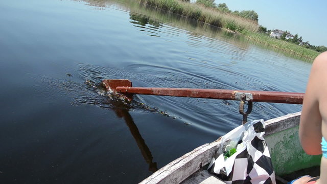 woman rowing with old oar in the water  formed ripples