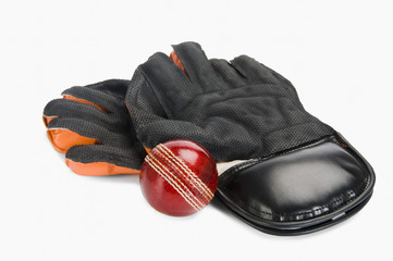 Close-up of a cricket ball with a pair of wicket keeping gloves
