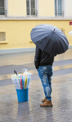 Man selling umbrellas stood in street