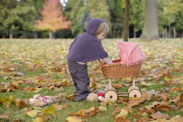 little girl playing with a pram in the park