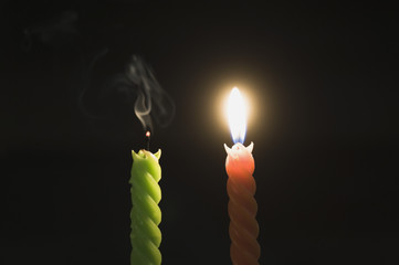 Close-up of a lit candle with an extinguished candle