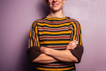 Happy young woman standing with her arms crossed