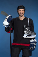 Smiling hockey player with skates over shoulder
