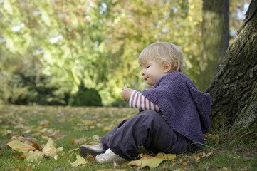 little girl eating a biscuit , outdoors in the park