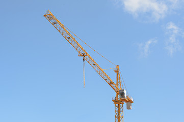 Crane at construction site against blue sky.