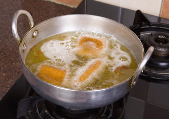 Close-up of pakoras being fried in a pan on a stove