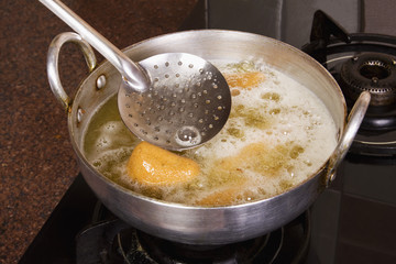 Close-up of pakoras being fried in a pan on a stove