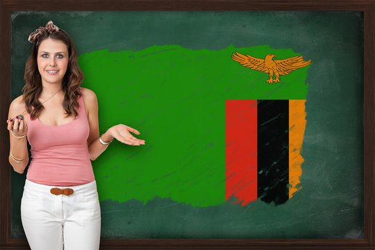 Beautiful And Smiling Woman Showing Flag Of Zambia On Blackboard