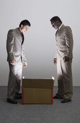 Two businessmen looking into an illuminated cardboard box