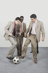 Four businessmen playing with a soccer ball