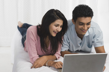 Couple using a laptop on the bed