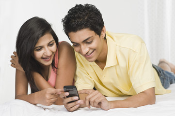 Couple looking at a mobile phone on the bed
