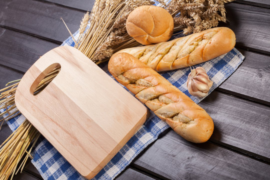 Baguettes lying on a wooden chopping board.