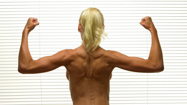 Rear view of blonde woman flexing back muscles