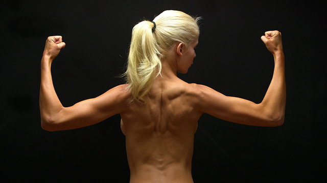 Rear view of blonde woman flexing back muscles