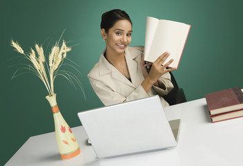 Businesswoman showing a book and smiling in an office