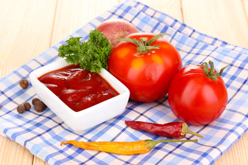 Ketchup and ripe tomatoes on wooden table