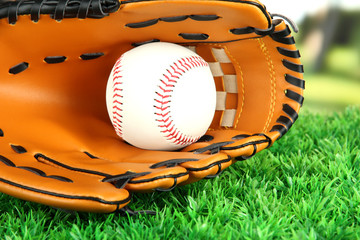 Baseball glove and ball on grass in park