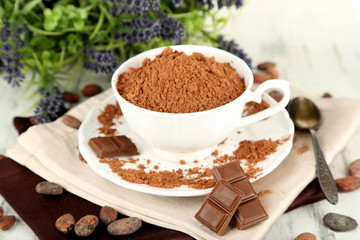 Cocoa powder in cup on napkin on wooden table