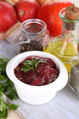 Raw liver in bowl with spices and condiments