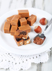 Many toffee on plate on napkin on wooden table