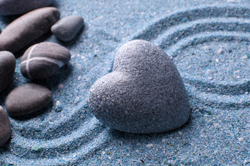 Grey zen stone in shape of heart, on sand background