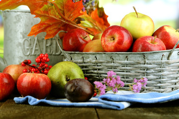 Juicy apples in basket on table on natural background