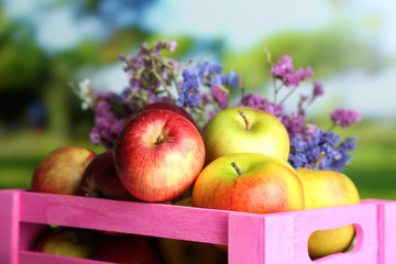 Juicy apples in box on white wooden table on natural background