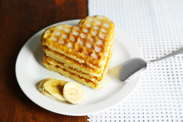 Sweet Belgium waffles with banana, on wooden table background