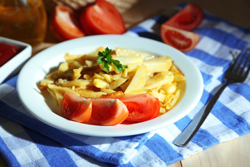 Ruddy fried potatoes on plate on wooden table close-up