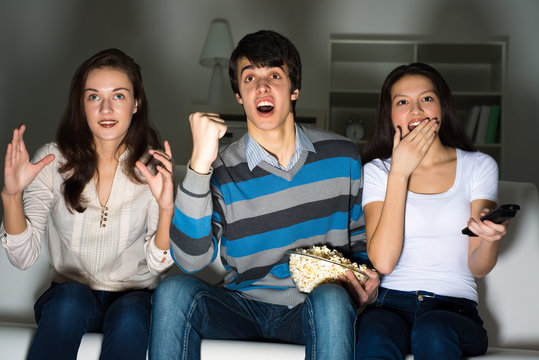 group of young people watching TV on the couch