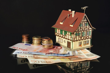 Immobilie mit Eurostücken und Euroscheinen