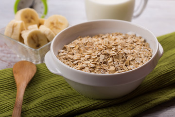 Oat flakes in bowl with banana and milk