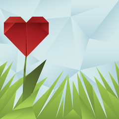 Red origami heart around grass on blue crumpled background