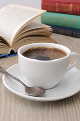 A cup of coffee on a table among books