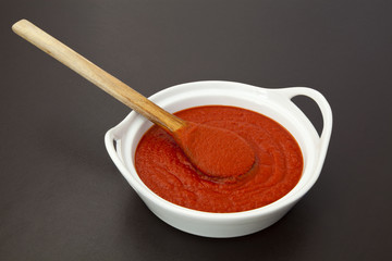 Tomato sauce in a bowl with wooden spoon