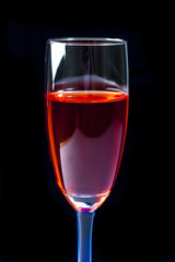 The glass of red wine on  black with reflections