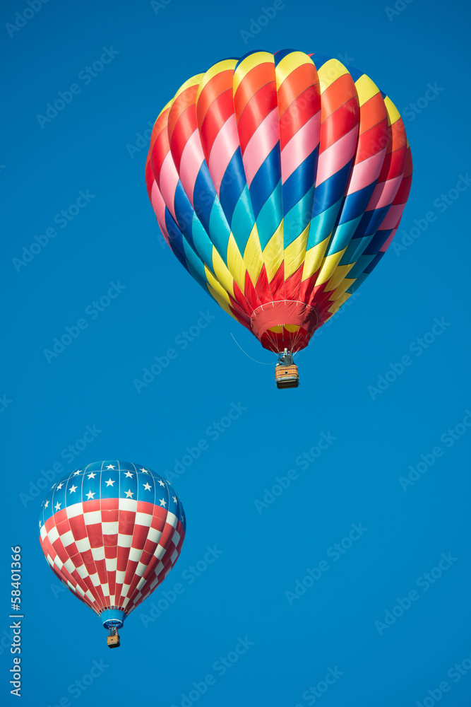 Wall mural two brightly colored hot air balloons with a sky blue background