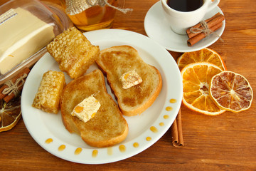 White bread toast with honey and cup of coffee on wooden table