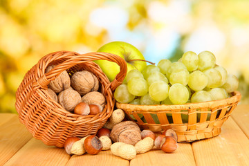Grape in basket with nuts on wooden table