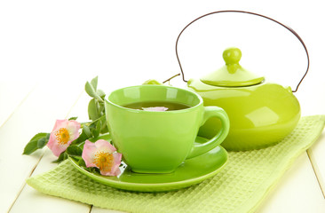 Cup and teapot of herbal tea with hip rose flowers