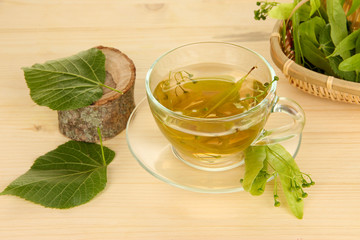 Glass cup of tea with linden on wooden table close-up