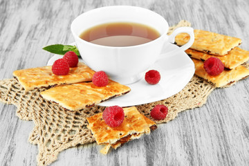 Cup of tea with cookies and raspberries on table close-up