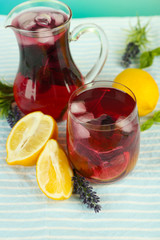 Red basil lemonade in jug and glass, on wooden background
