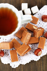 Many toffee and cup of tea on napkin on wooden table