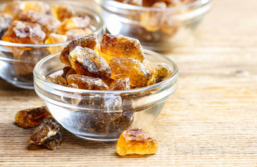 Granulated brown sugar in transparent glass bowl on wooden table