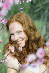 Fototapeta premium beautiful red-haired girl among the flowering trees