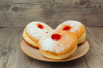 Donut for jewish holiday hanukkah on plate on wooden background