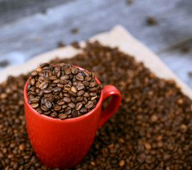Cup of coffee filled with coffee beans against wooden background