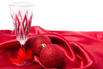 Red christmas balls and champagne glass on a red silk cloth